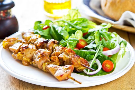 Grilled chicken skewer with rocket salad by bread