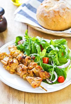 Grilled chicken skewer with rocket salad by bread