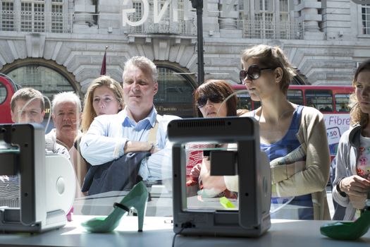 LONDON, UK - MAY 31: Pedestrians intrigued with 3D printer in United Nude shop window. The shop, based in Regent Street, has a line of products created on site by 3D printers. May 31, 2014 in London.