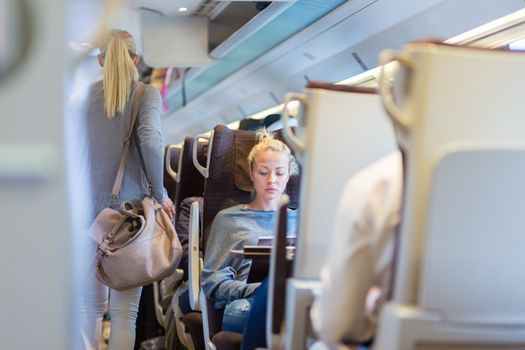 Blonde casual caucasian lady traveling by train. Train full of passengers going to work by public transport at rush hour.