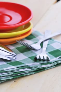 Close-up of stainless fork and spoon on tablecloth with red,yellow, orange plate.
