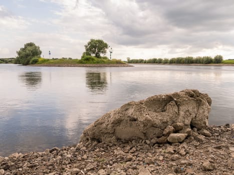 Low point of view by Large rock by quiet river in Doesburg, Holland