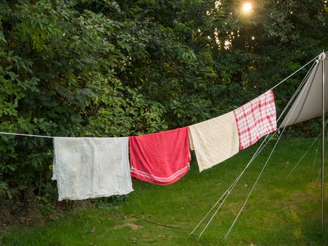 A line of towels hanging out to dry outside a tent on a summer evening