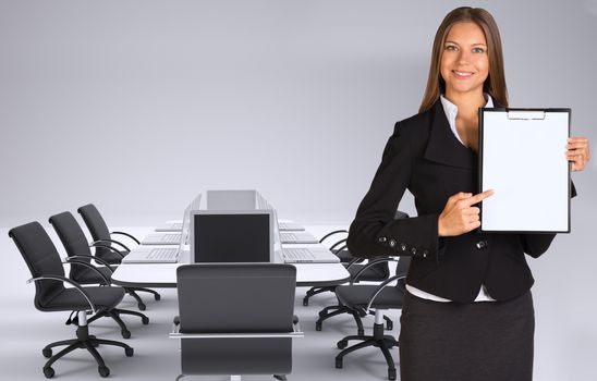 Businesswoman holding paper holder. Conference table, chairs and laptops as backdrop