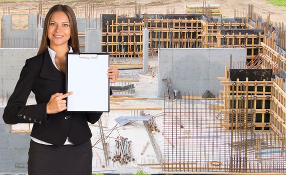 Businesswoman holding paper holder. Walls of the steel reinforcement and concrete as backdrop