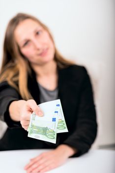 Defocused young woman offering money