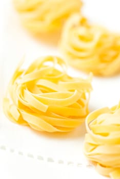 Nests of dry pasta tagliatelle on white table cloth