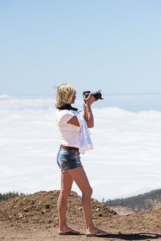 Young woman with camera above clouds