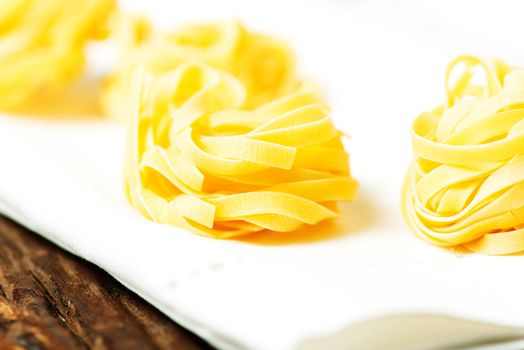 Nests of dry pasta tagliatelle on white table cloth