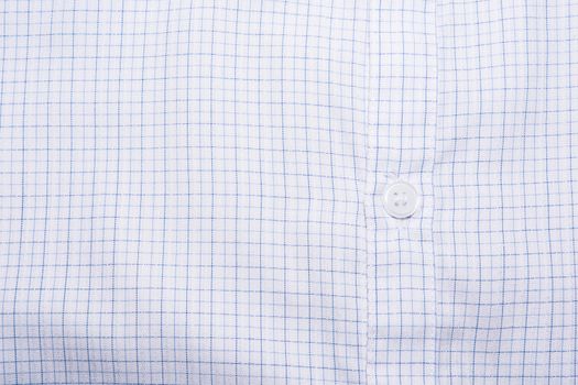 Close-up photograph of a white button on a striped shirt pattern.