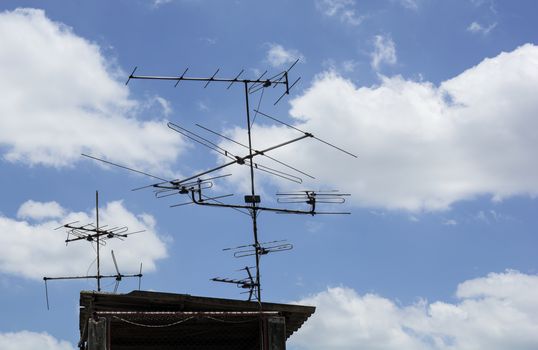 the Antenna TV on the top roof of the house under the blue sky and white clouds