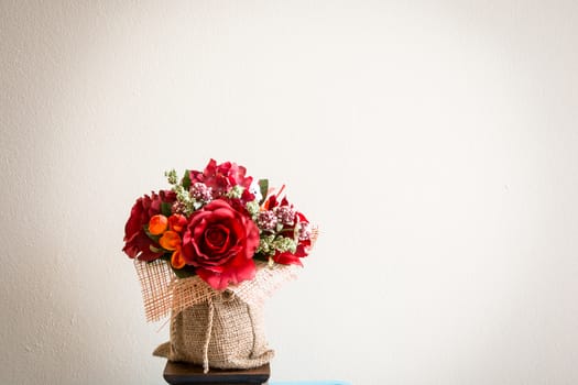 the colouful flowers with green leaves in the fabric jar