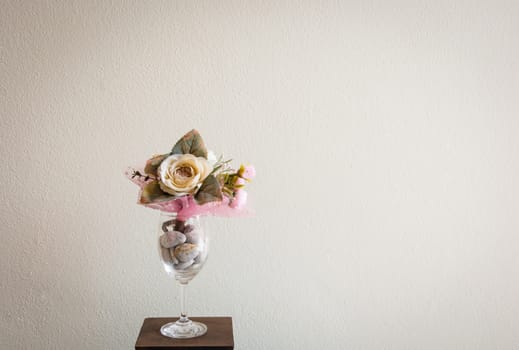 the colouful flowers with green leaves in the wine glass