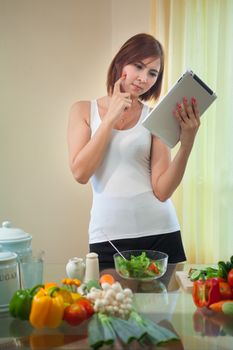 Young asian woman In Kitchen Following Recipe On Digital Tablet