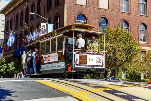 SAN FRANCISCO - OCT 06: Passengers enjoy a ride in a cable car on Oct 06, 2012 in front of famous Transamerica building in San Francisco. It is the oldest mechanical public transport in San Francisco which is in service since 1873. 