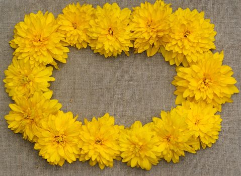 Frame of yellow flowers against a background of rough cloth