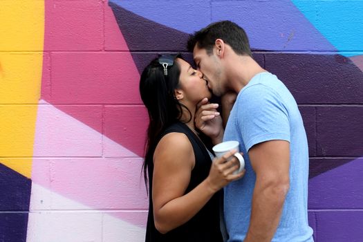 A in love couple kissing in front of a wall.