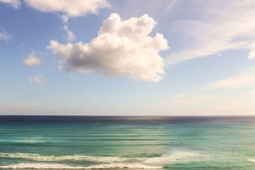 White clouds over surfers in the Pacific Ocean in Waikiki Beach in Honolulu, Hawaii