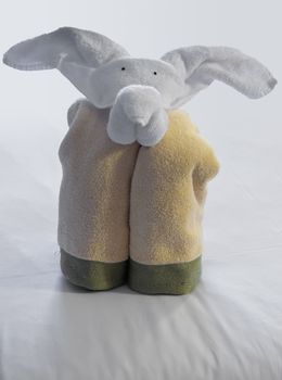 Unusual animal shaped like a elephant created from rolled and folded towels on top of bed sheets in hotel