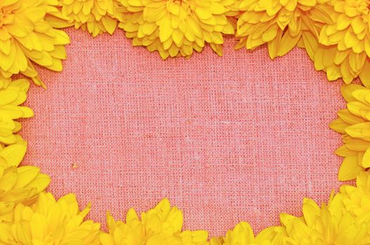 Frame of yellow flowers against a background of rough cloth