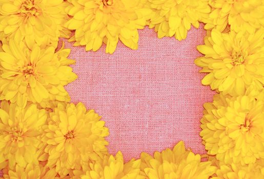 Frame of yellow flowers against a background of pink cloth