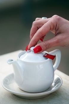 A woman opens a kettle with tea