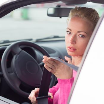 Safety first. Beautiful blonde caucasian lady fastening car seat belt.