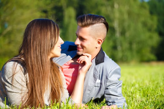 Happy smiling young couple embracing outdoor at sunny day