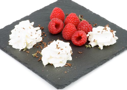 Delicious Dessert with Fresh Raspberries, Dairy Cream and Grated Chocolate on Black Plate closeup on white background