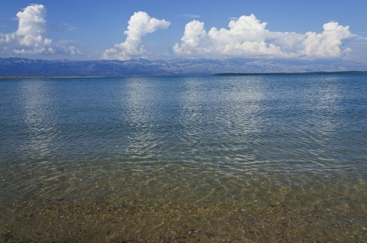 landscape of an empty sand beach in the summer day with clouds and mountains in the background