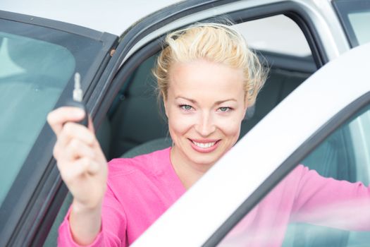 Woman driver showing car keys. Young female driving happy about her new car or drivers license. Caucasian model.