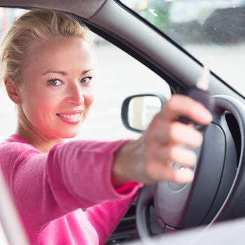 Woman driver showing car keys. Young female driving happy about her new car or drivers license. Caucasian model.