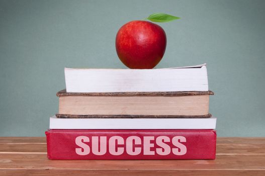 Pile of books next to a blackboard with the heading success