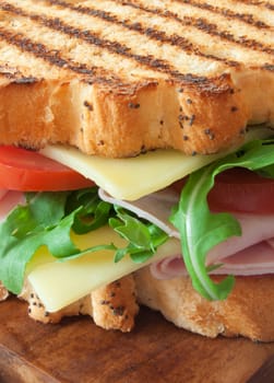 Grilled sandwich with ham and cheese on top of a chopping board 