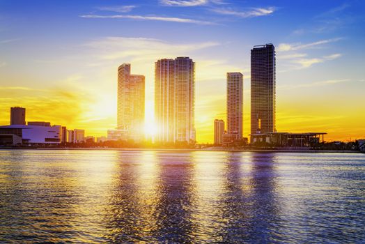 Miami city skyline panorama at dusk with urban skyscrapers over sea with reflection 