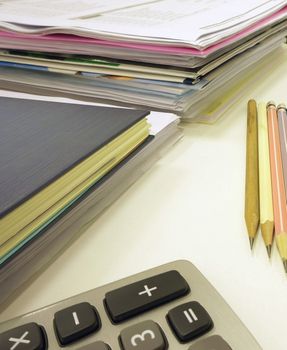 Office equipment such as calculators, pencil, abook on desk in office.                               