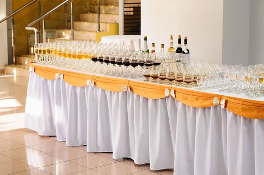 banquet table with alcohol drinks and rows of stemware