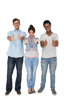 Full length portrait of three happy friends gesturing thumbs up over white background
