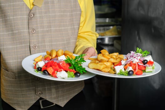 waiter at restaurant kitchen holding order of two dishes