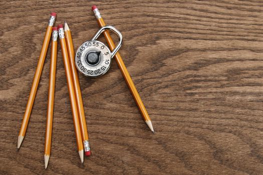 Pencils and school lock on wood surface