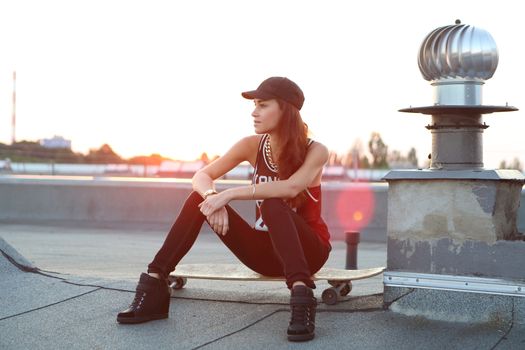 Young girl on the roof relaxes in the rays of the setting sun