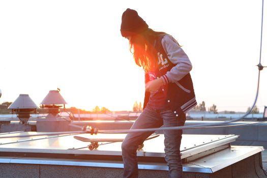 Young girl on the roof relaxes in the rays of the setting sun