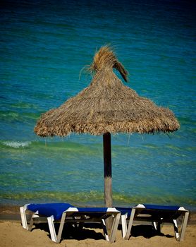 Beach Chairs and Thatched Umbrella on Blue Sea background Outdoors