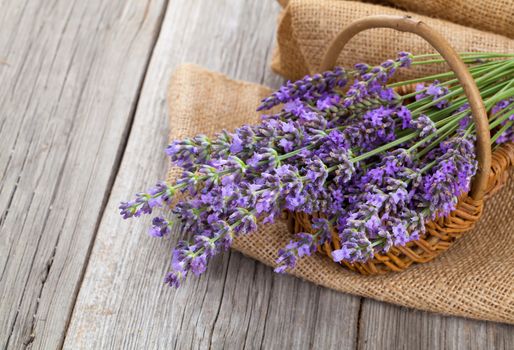 lavender flowers in a basket with burlap on the wooden background