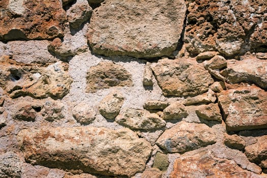 Fragment of the ancient stone wall executed from stones of various form and the size. Background image.