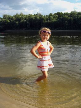 little girl standing in the beautiful river