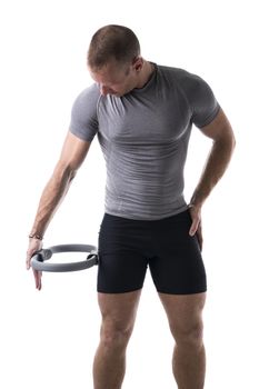 Young muscular man exercising with Pilates ring against thigh, isolated on white