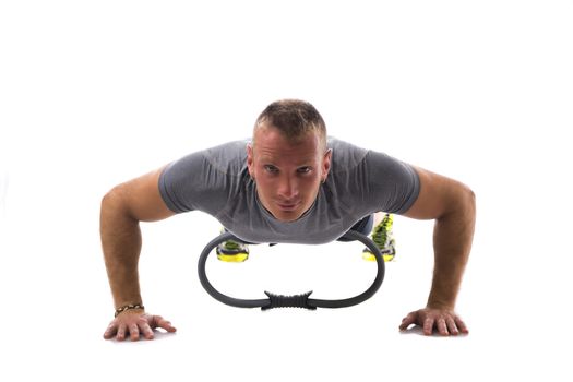 Young blond muscular man exercising on the floor with Pilates ring isolated on white