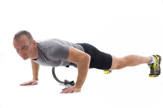 Young blond muscular man exercising on the floor with Pilates ring isolated on white