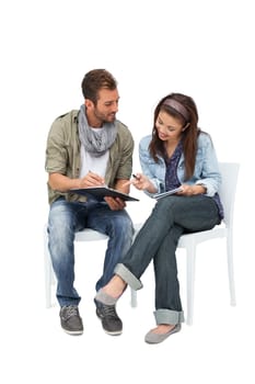 Full length of a cool young couple writing in notepads over white background